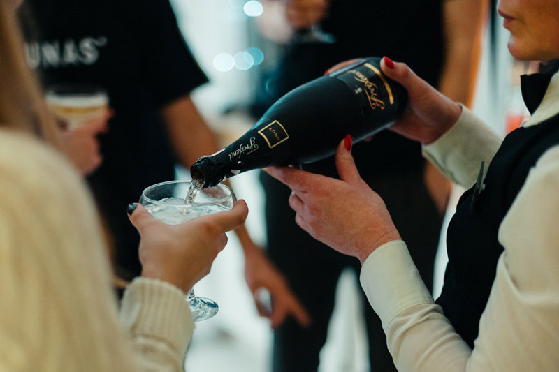 bartender pours champagne in New Year glasses of the company's employees