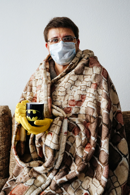 CG artist Sergey in a mask and protective gloves with a cup of tea staying at home